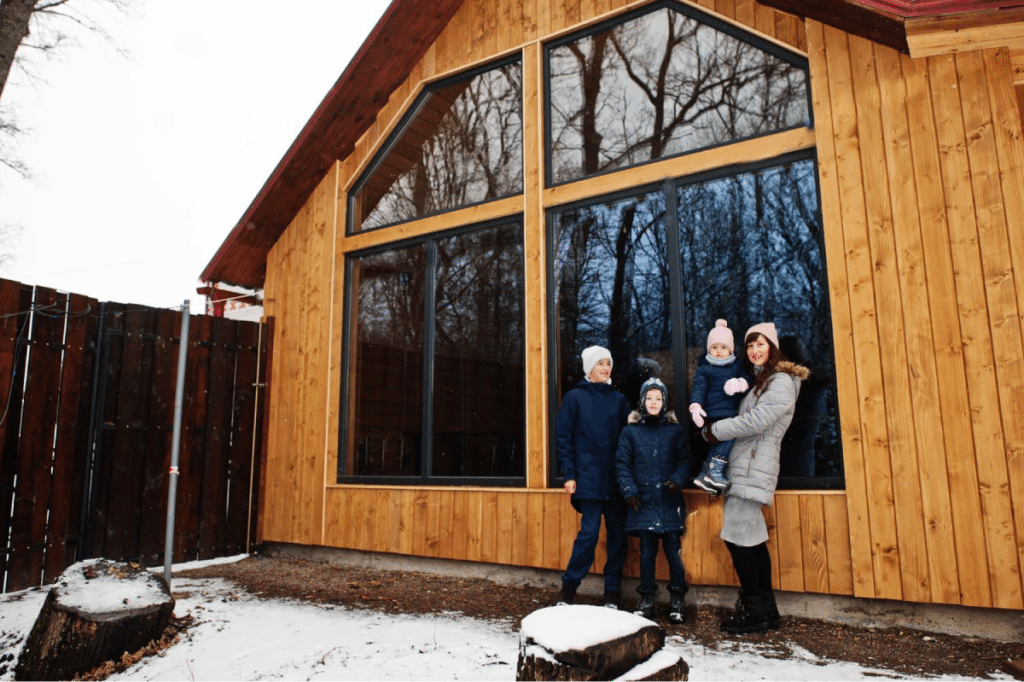 Family standing outside a wooden home, showing potential for termite risk in wooden structures.