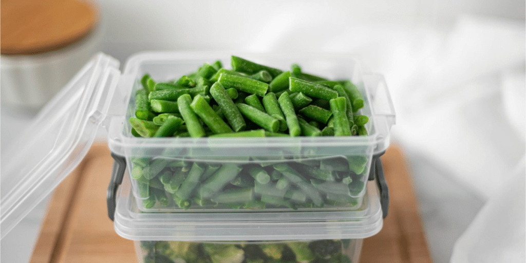 Fresh green beans stored in a plastic container.